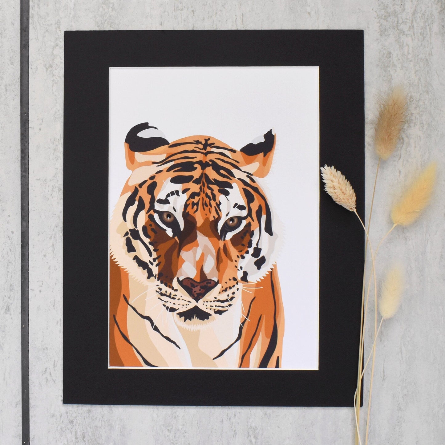 Framed artwork of a tiger on a textured wall with dried plants.
