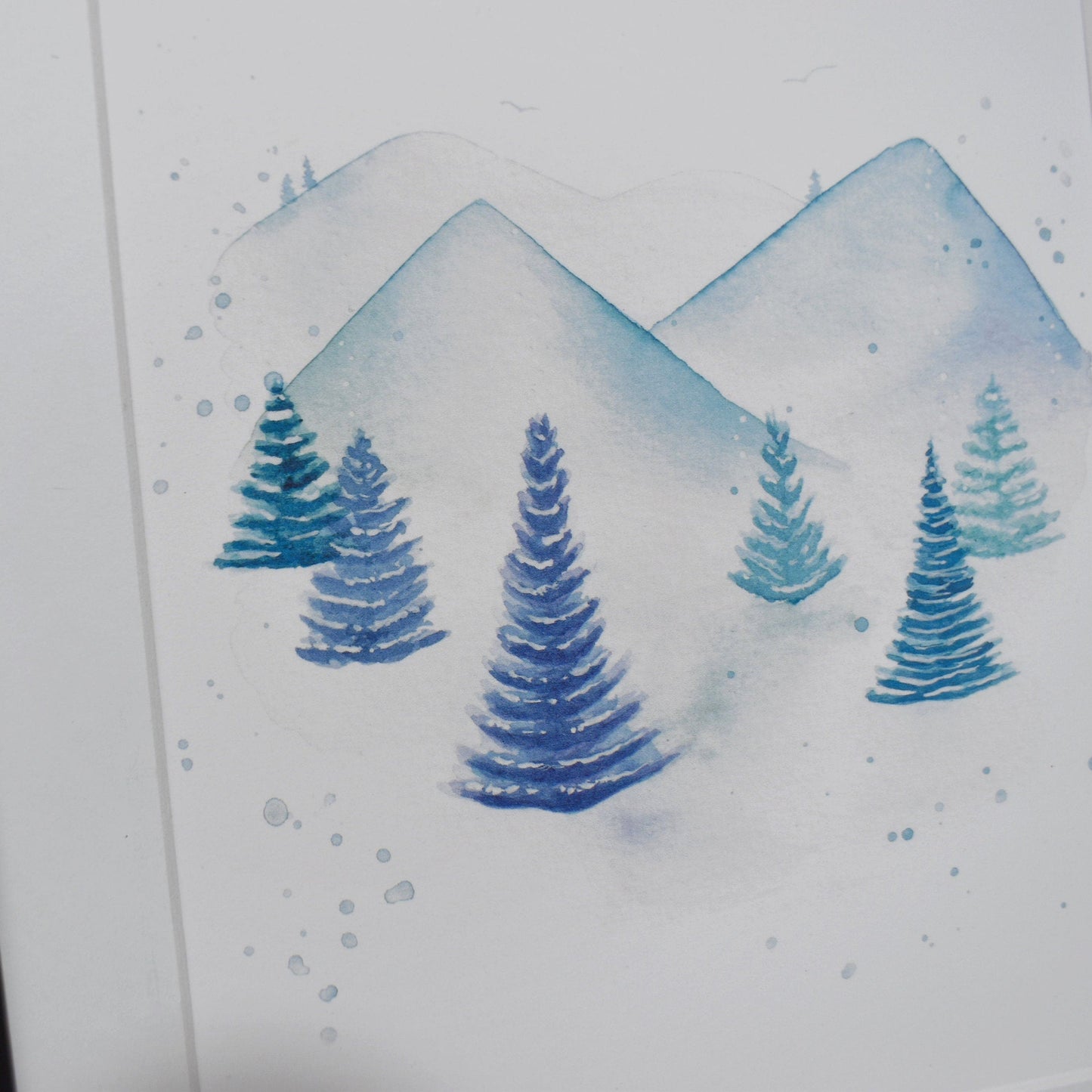 Framed artwork of blue trees and mountains on a white background