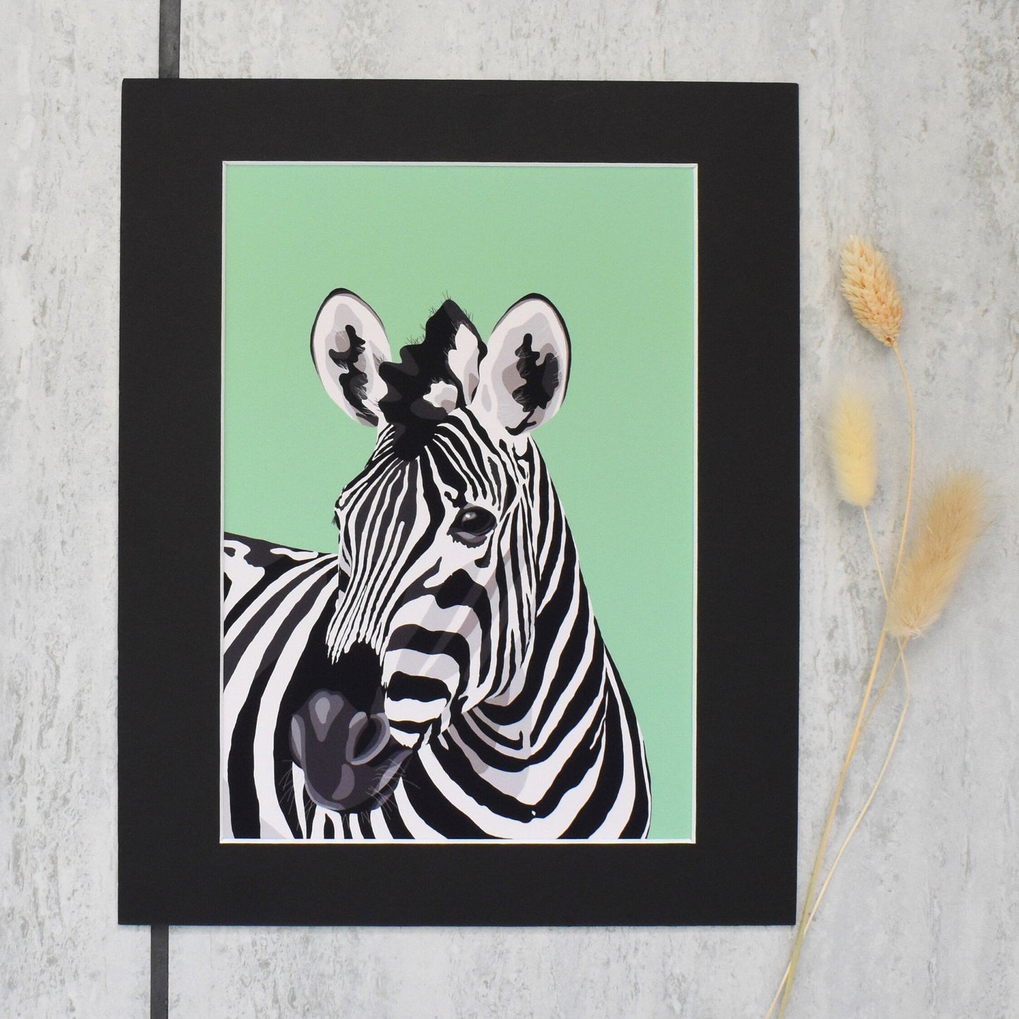Framed artwork of a zebra on a light green background with a black frame.