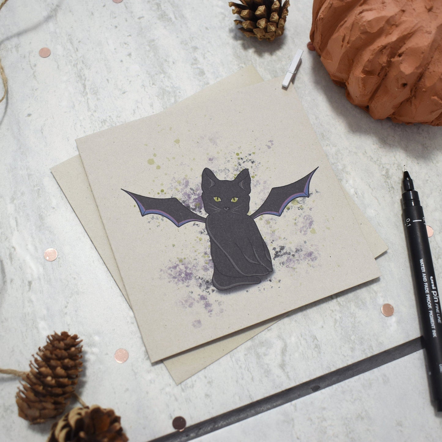 Greeting card with a bat illustration on a textured surface with decorative items.