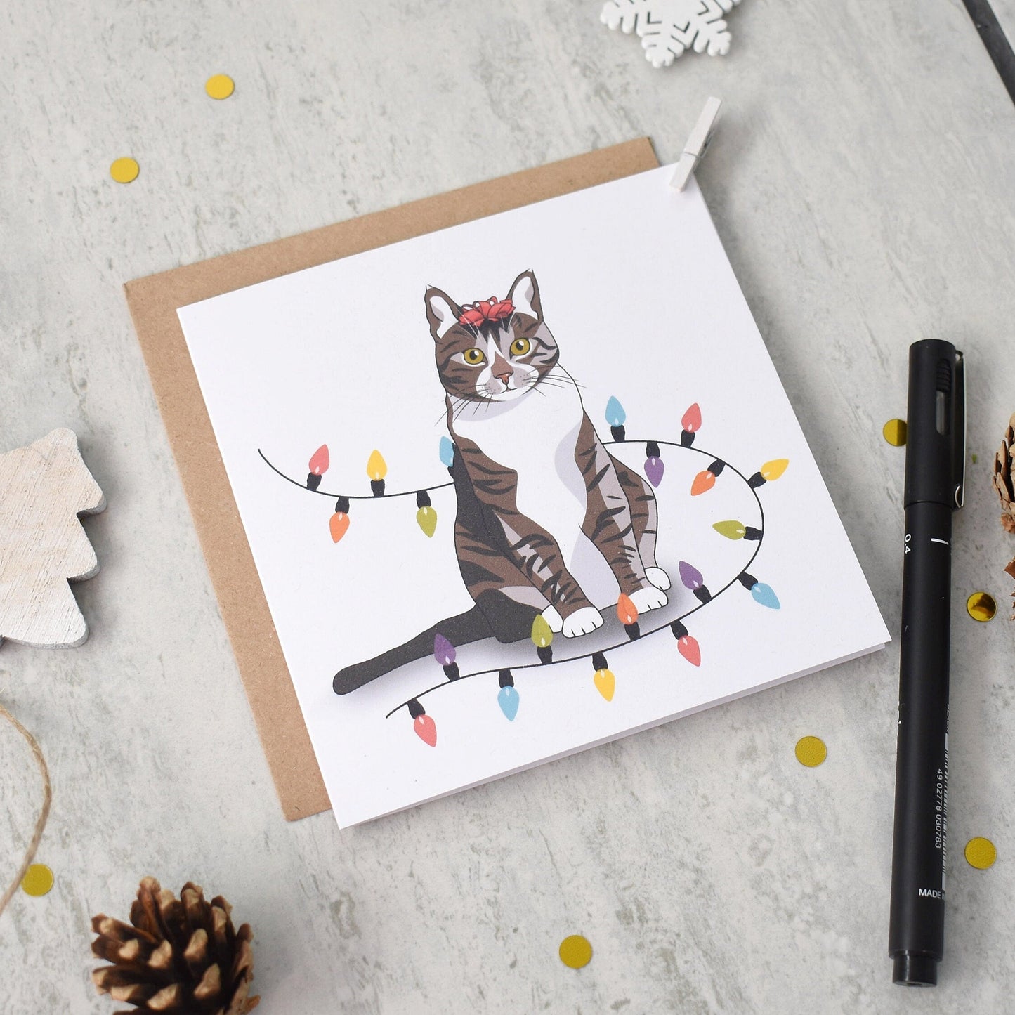 Greeting card with a cat illustration on a light gray surface with decorative items.