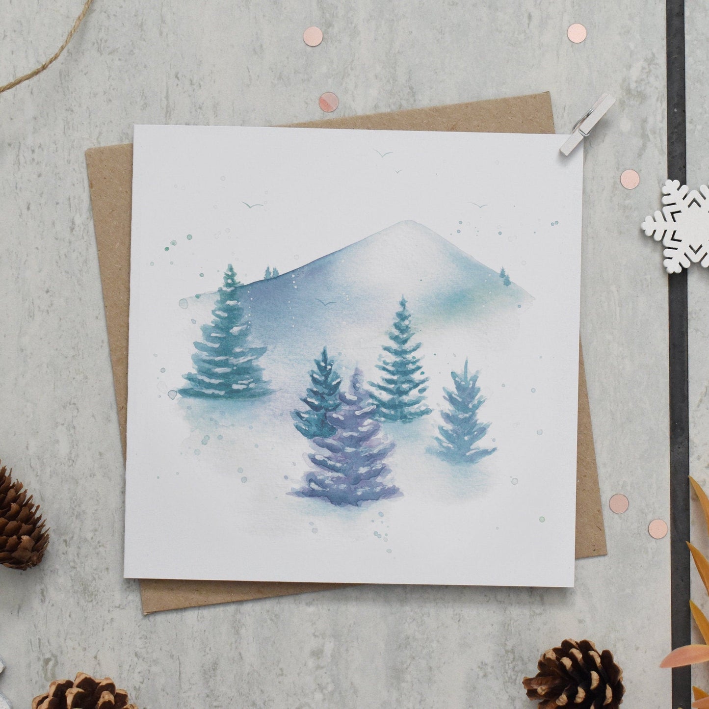Greeting card with winter scene design on a textured surface with decorative elements.