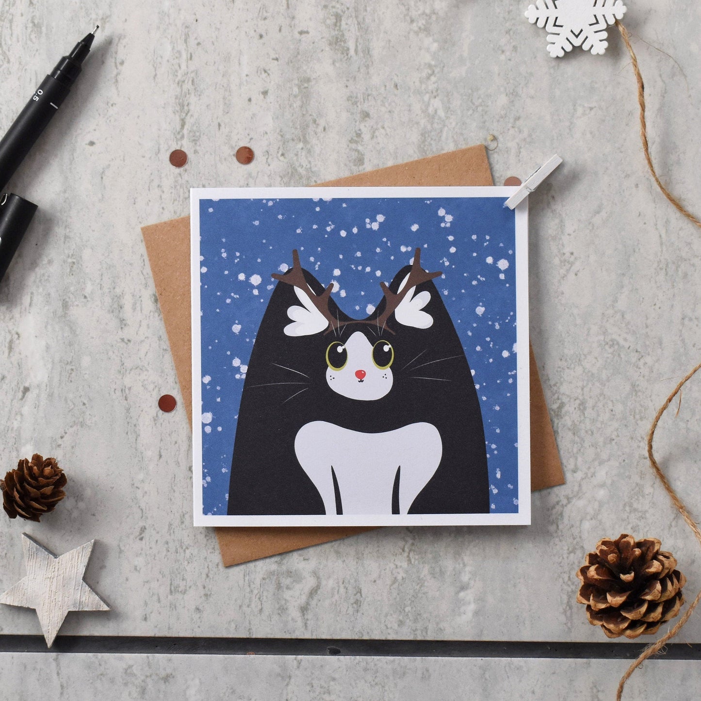 Greeting card with a cat illustration on a textured surface with decorative items.