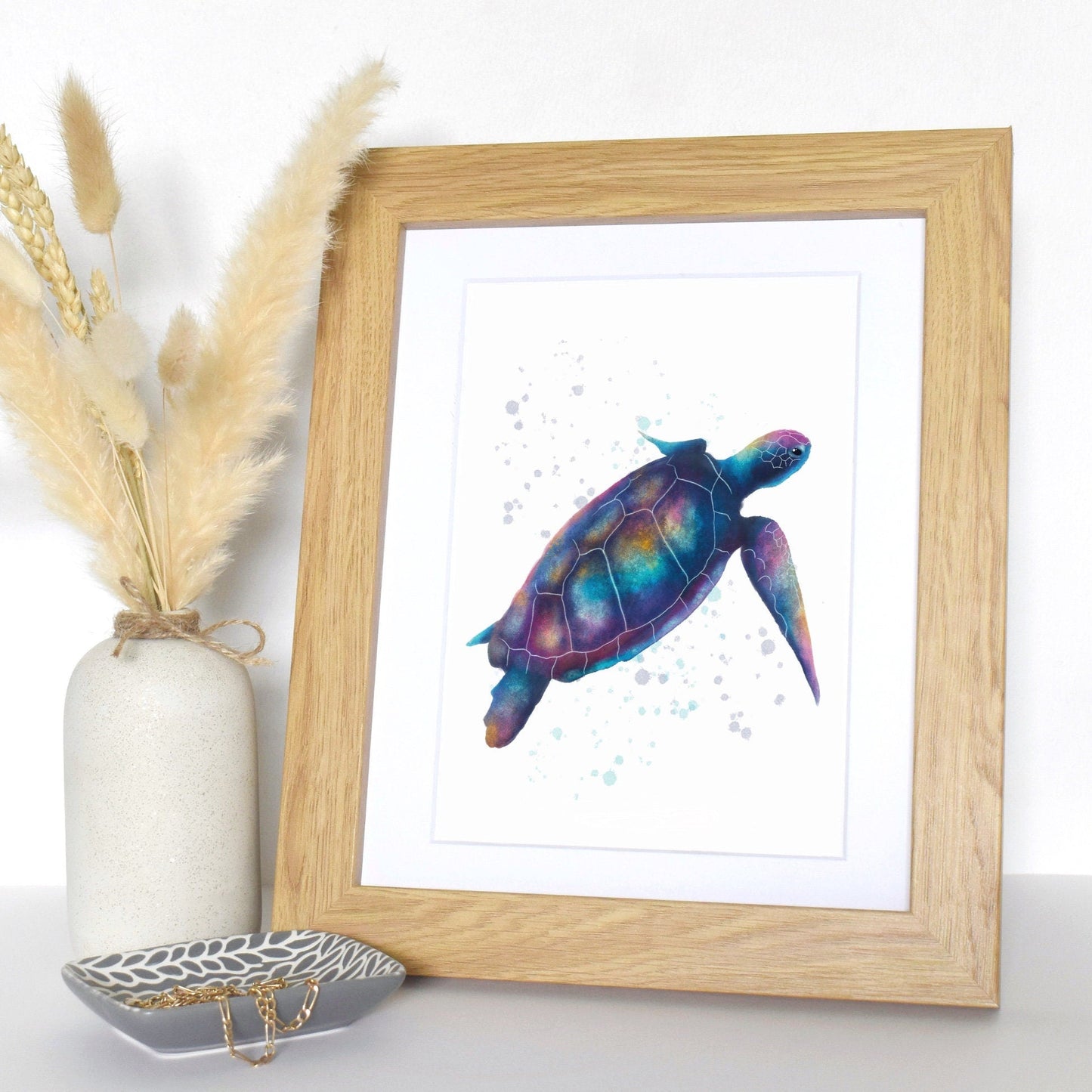 Framed artwork of a colorful turtle on a white wall with decorative elements.