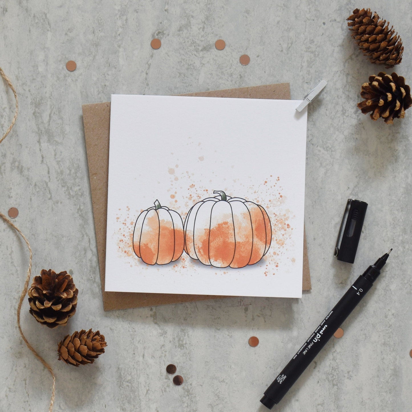 Greeting card with pumpkins and pinecones on a textured surface