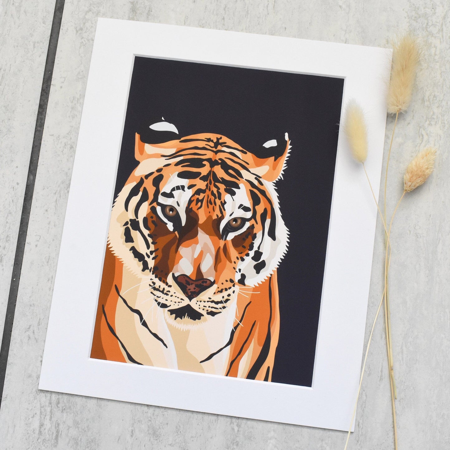 Framed artwork of a tiger on a textured surface with dried plants.