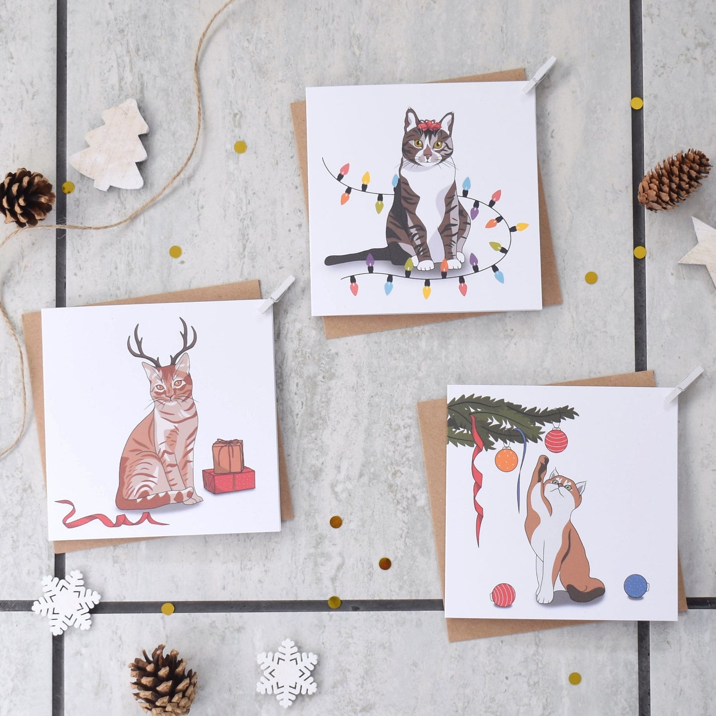 Three Christmas-themed greeting cards with cats on a textured surface with decorative elements.