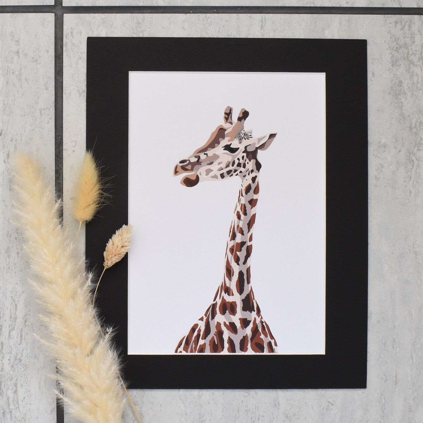 Framed artwork of a giraffe on a textured wall with pampas grass.