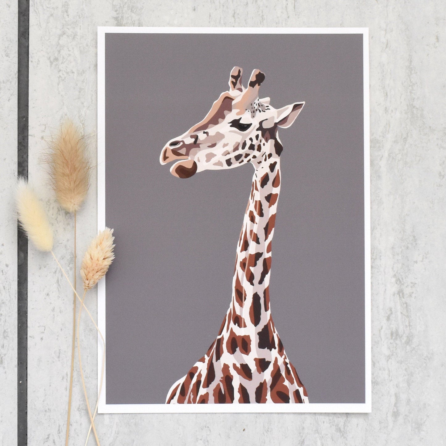 Framed artwork of a giraffe on a gray wall with decorative elements.