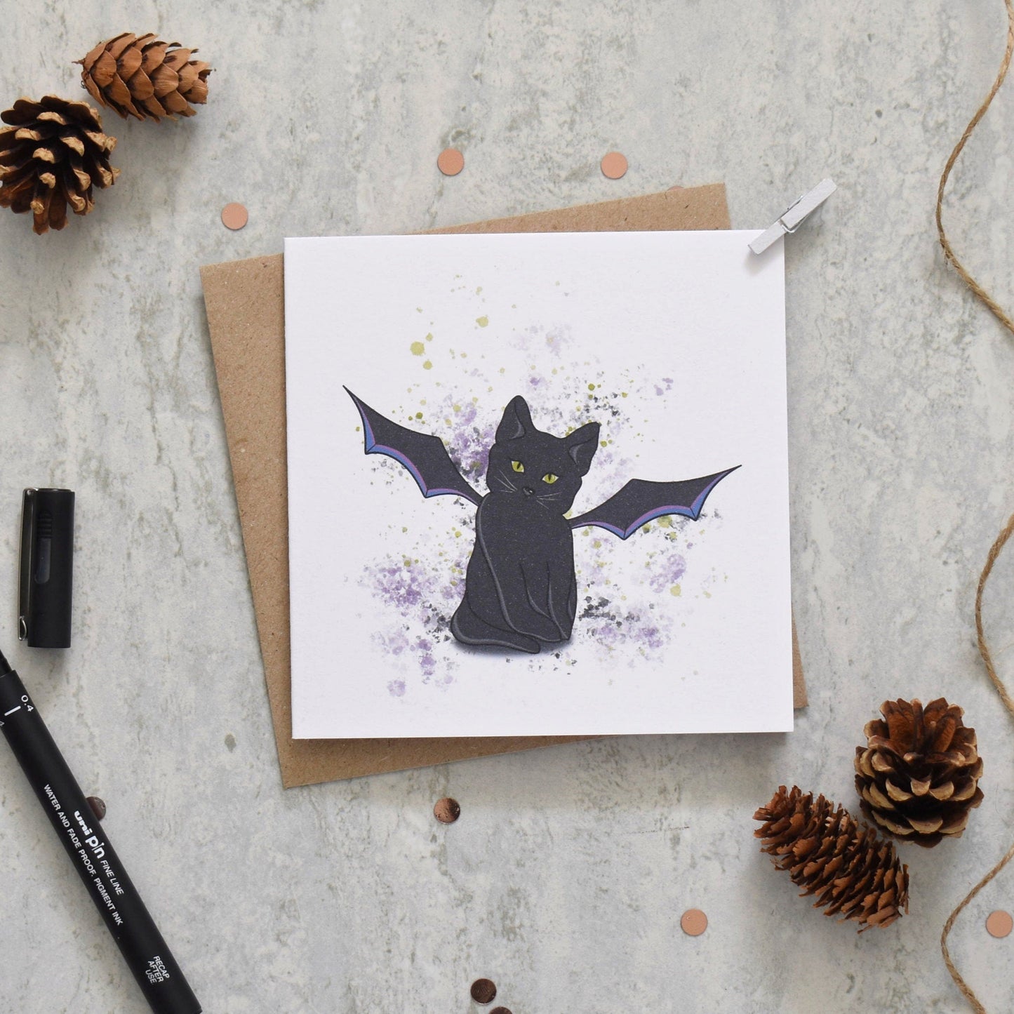Greeting card with a black cat design on a textured surface with decorative elements.