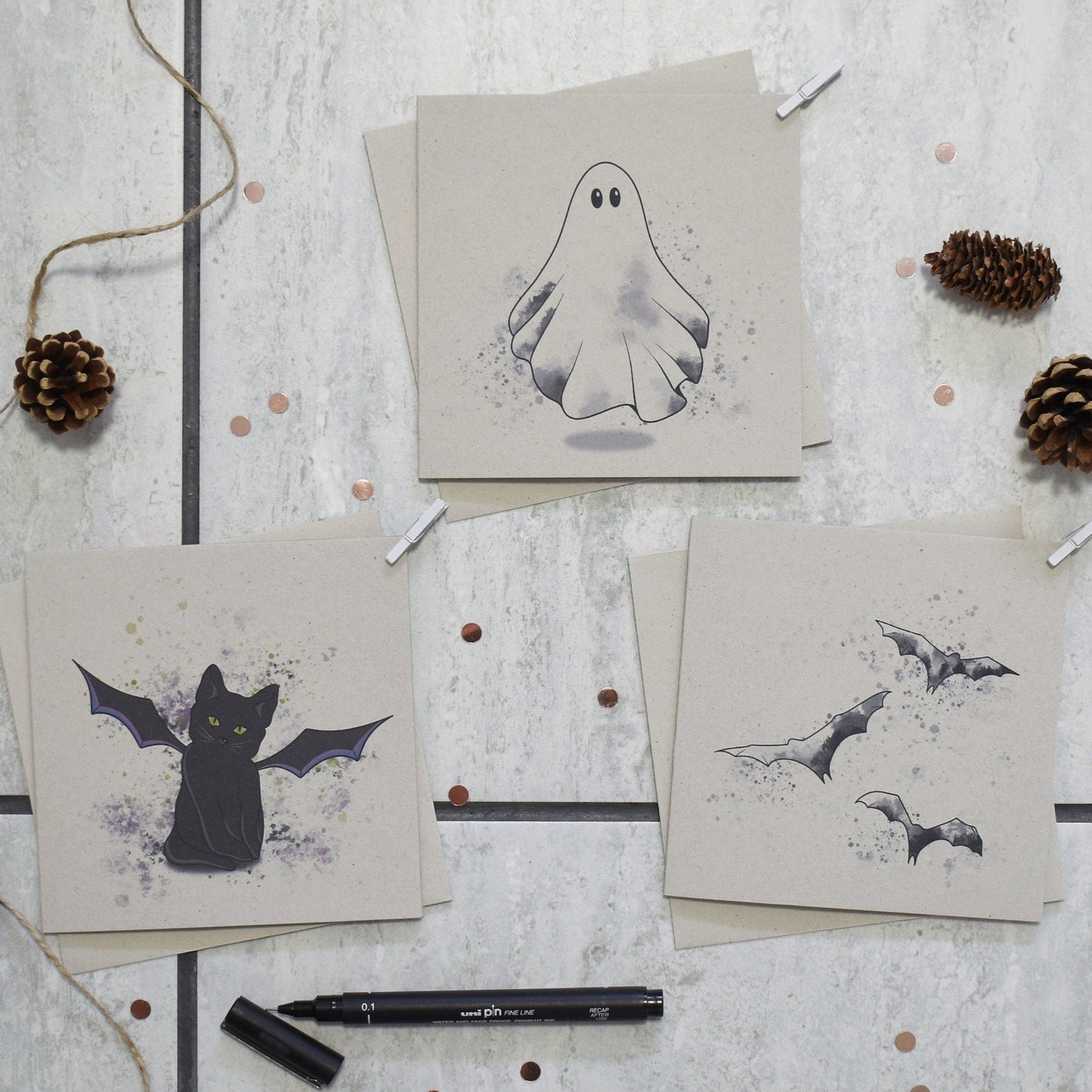 Three greeting cards with Halloween-themed illustrations on a textured surface.