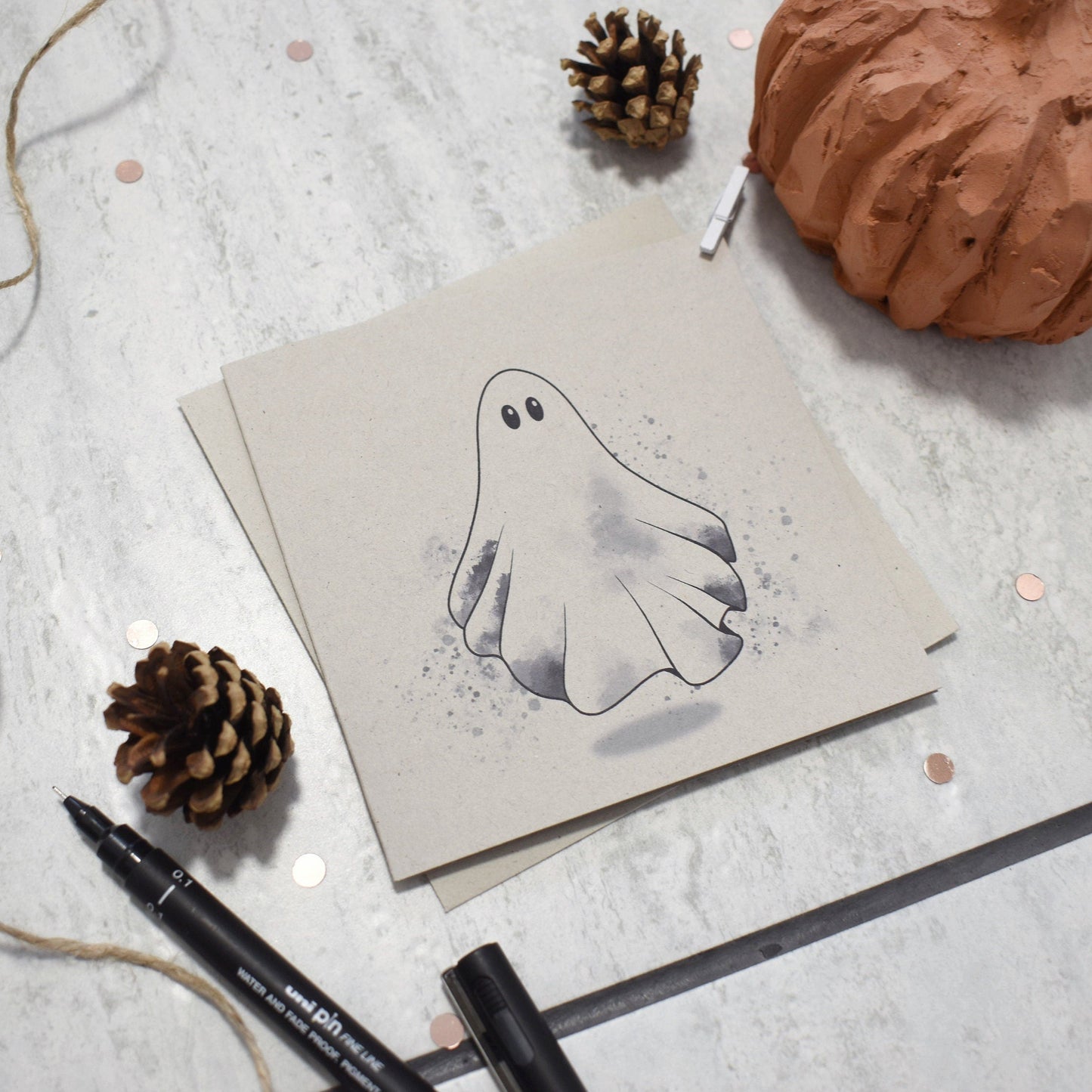 Hand-drawn ghost illustration on a card with decorative elements on a light surface