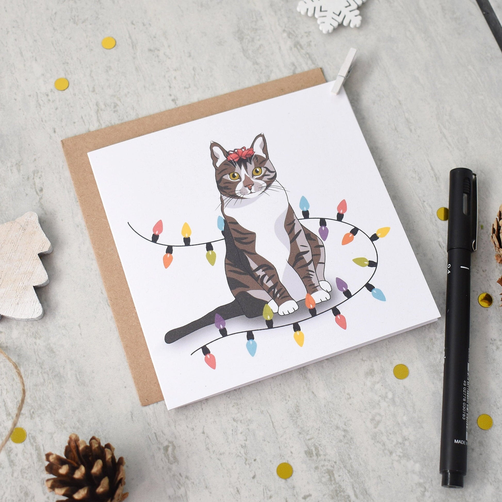 Greeting card with a cat illustration on a light gray surface with decorative items.