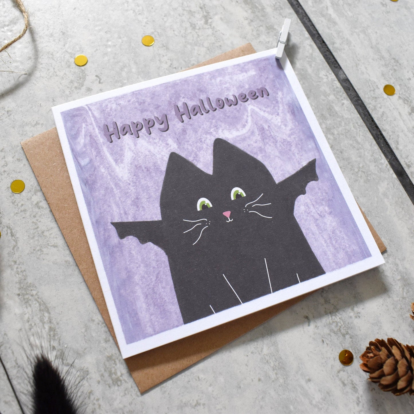 Halloween card with a black cat design on a gray surface with decorative elements.