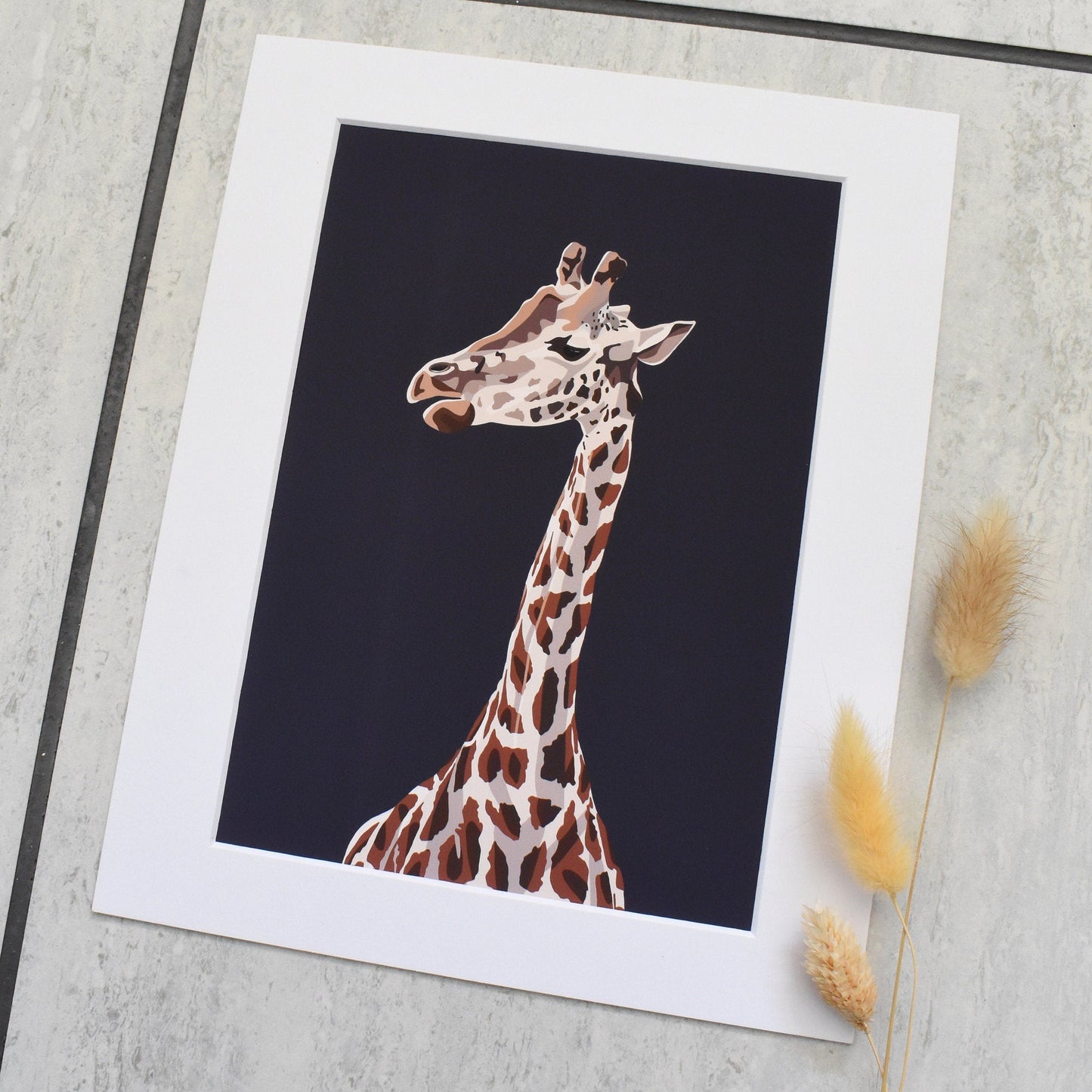 Giraffe illustration on a white card with a black background, placed on a textured surface.