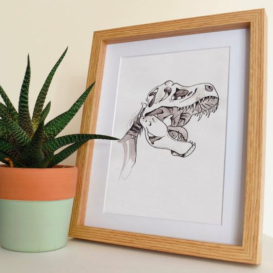 Framed dinosaur skeleton print next to a potted plant on a light surface with a neutral background