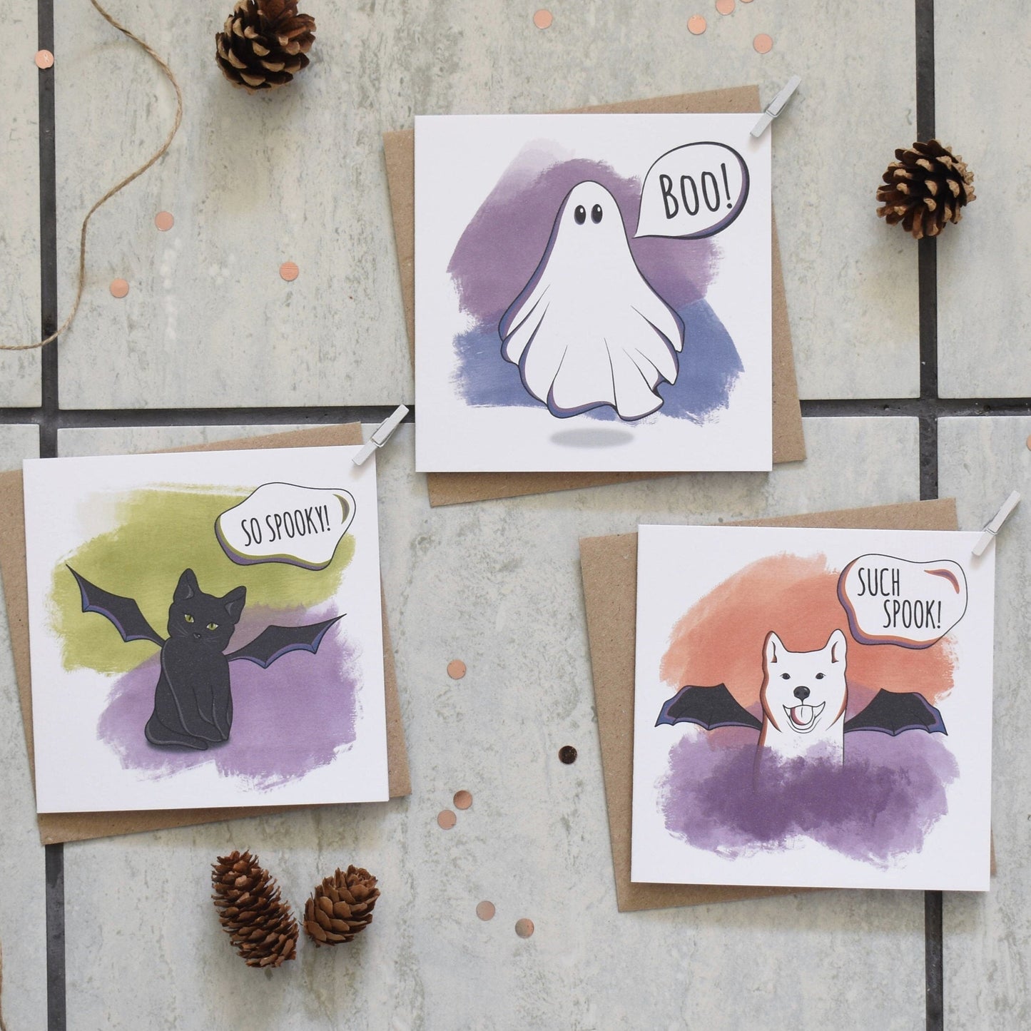 Three Halloween-themed greeting cards with a ghost, bat, and dog illustration on a textured surface.