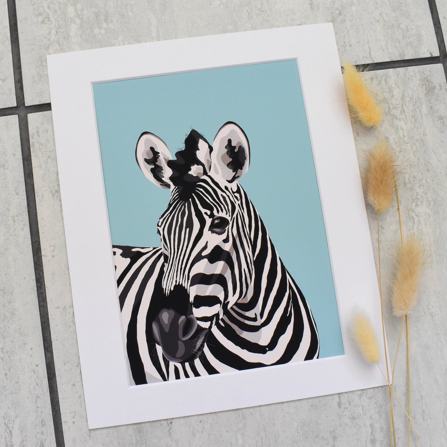 Zebra illustration on a blue background with white border, placed on a tiled surface.