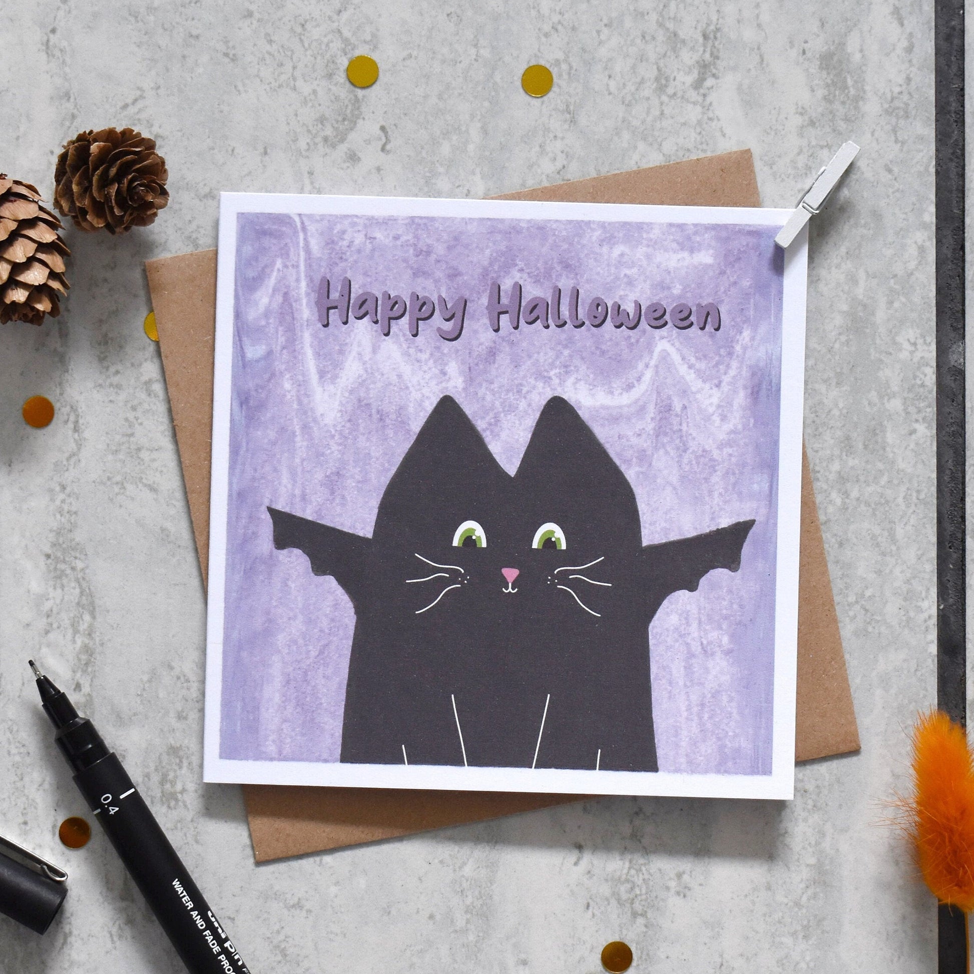 Halloween card with black cat design on a textured surface with decorative elements.
