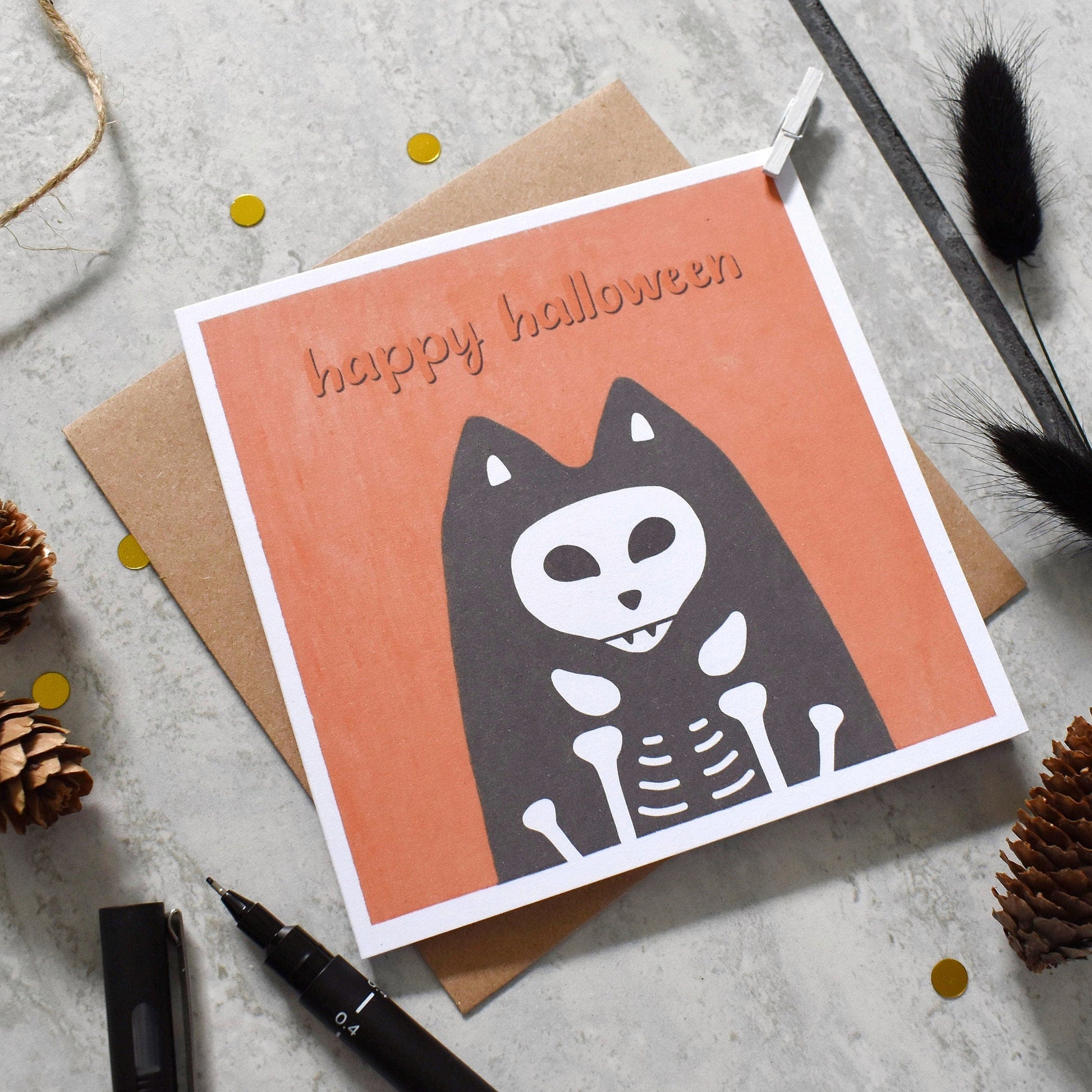 Halloween card with skeleton cat design on a textured surface with decorative elements.