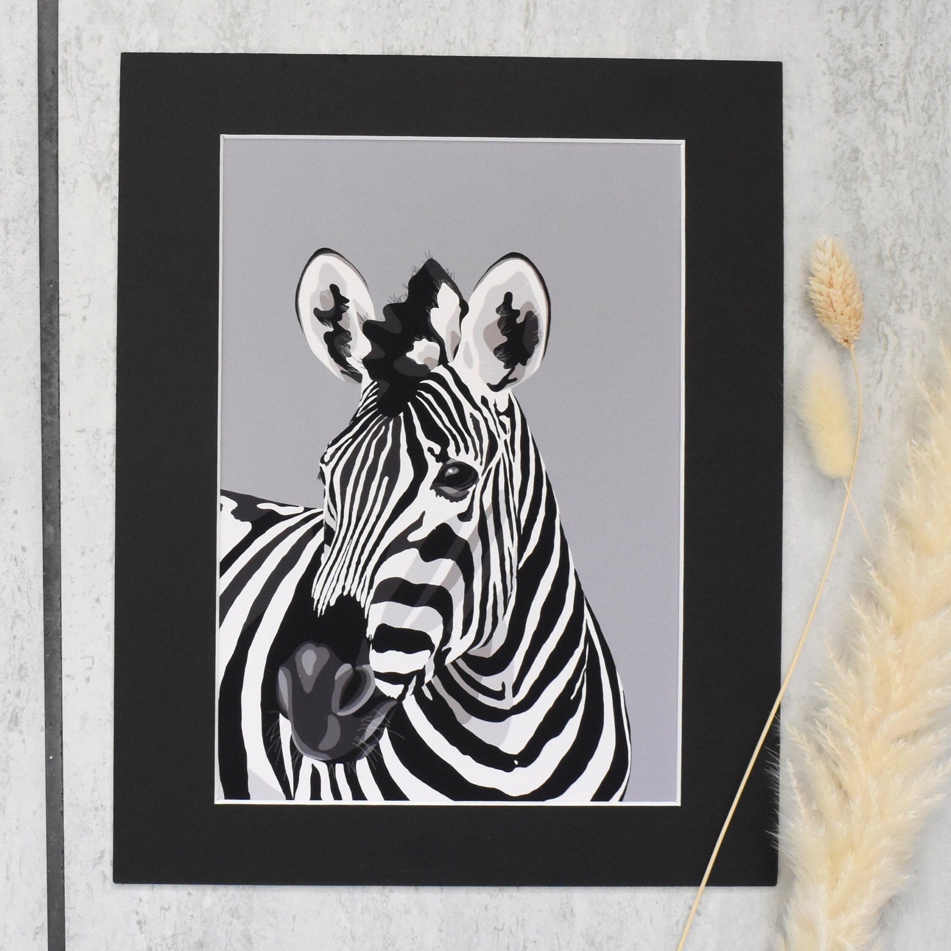 Framed black and white zebra print on a textured wall with dried plants.
