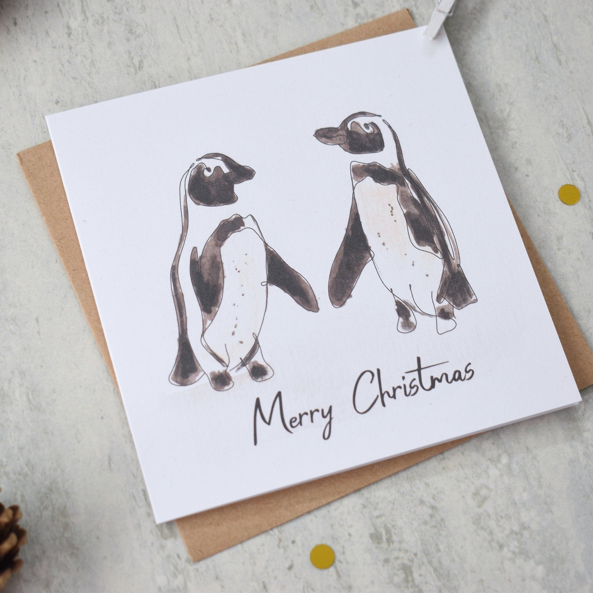Christmas card with penguin illustration and 'Merry Christmas' text on a light background.