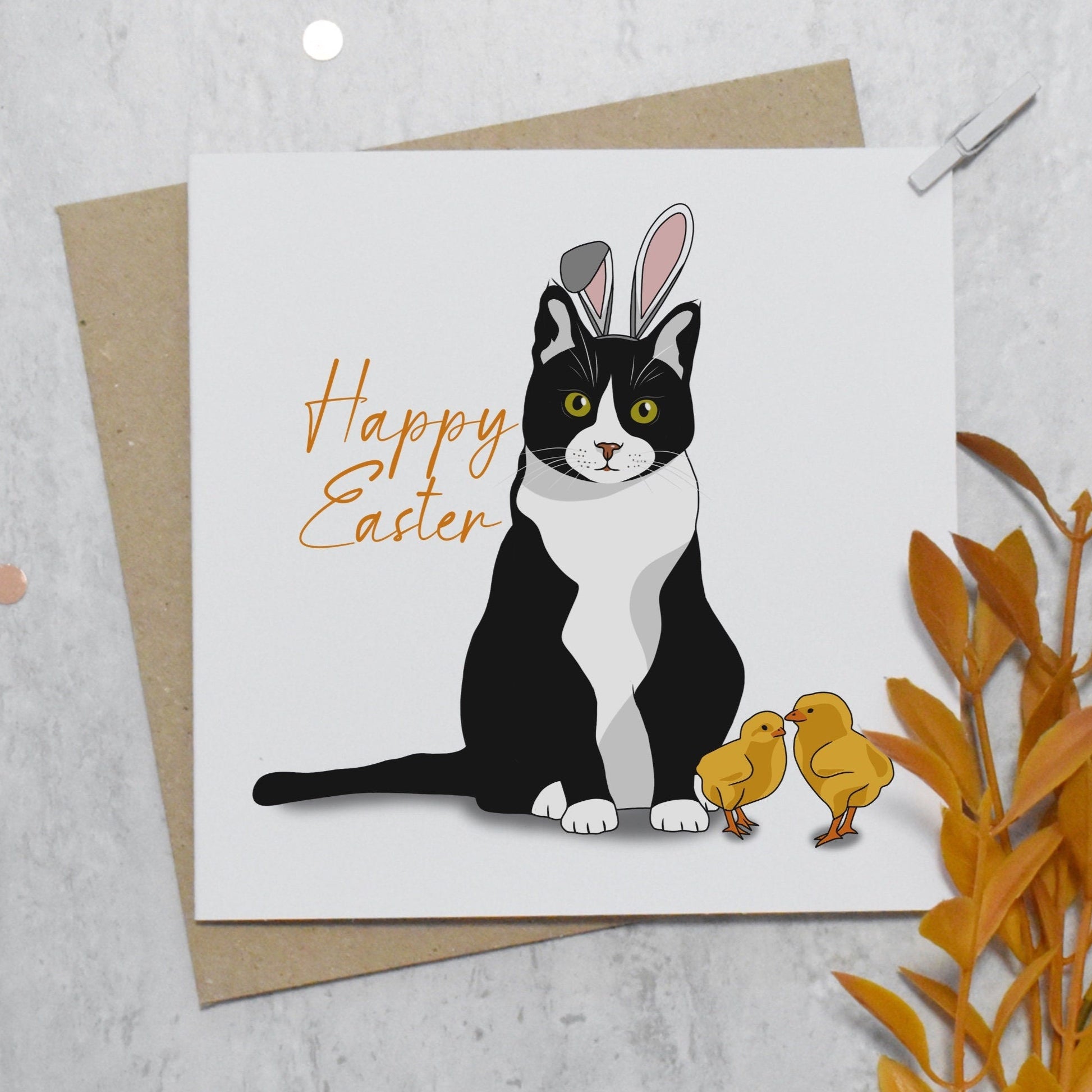 Greeting card with a cat wearing bunny ears and 'Happy Easter' text, on a light gray background.